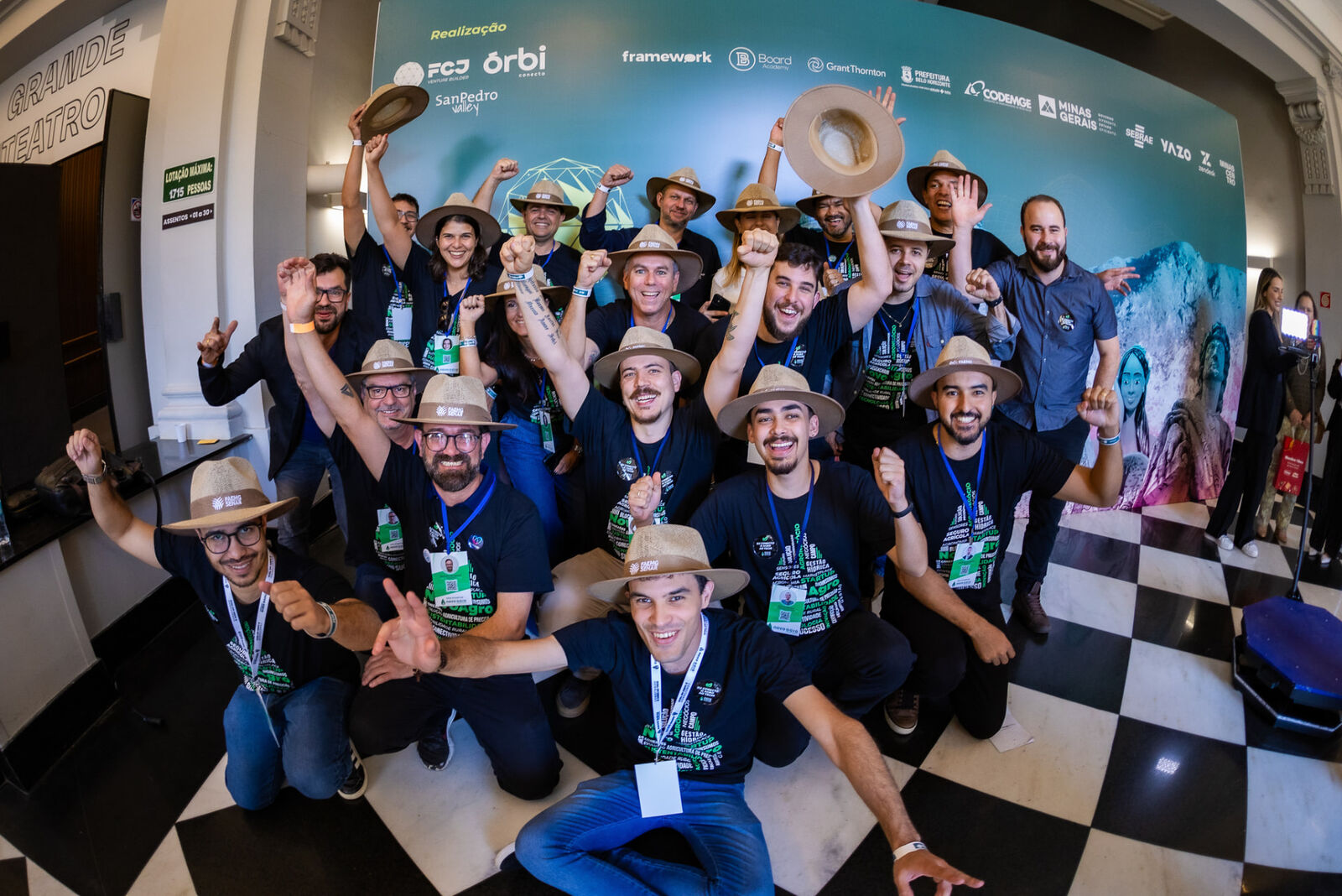 Grupo de participantes comemorando no painel de realização