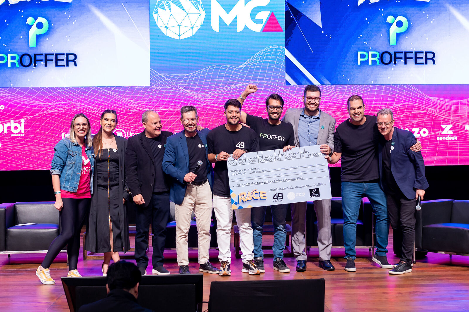 Startup premiada recebendo cheque simbólico no palco